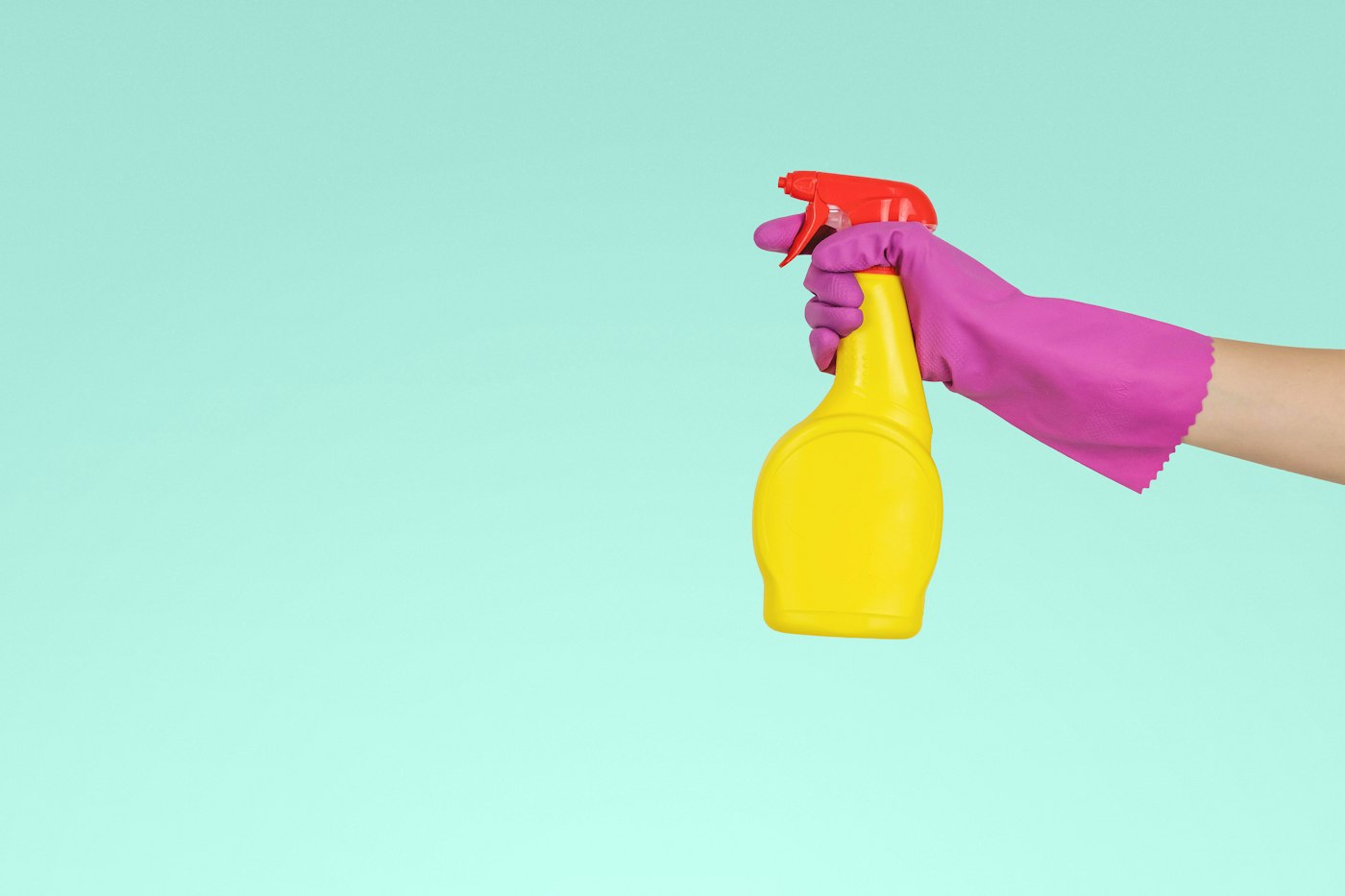 A gloved hand spraying cleaning liquid